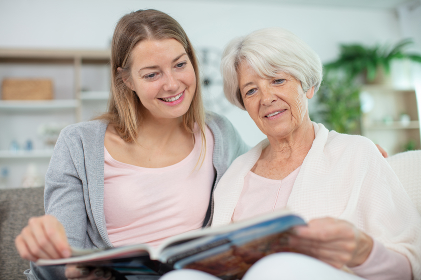 senior mother and attractive daughter looking at photo album