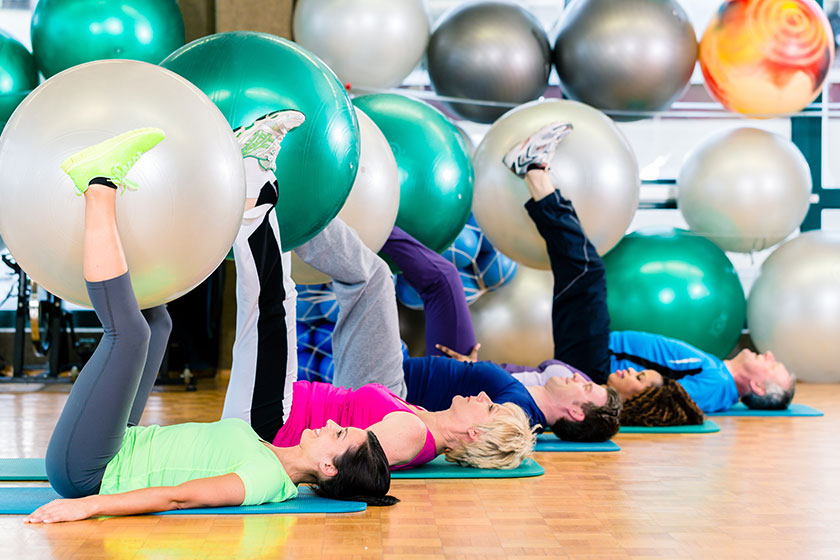 Young and senior people exercising with ball in gym