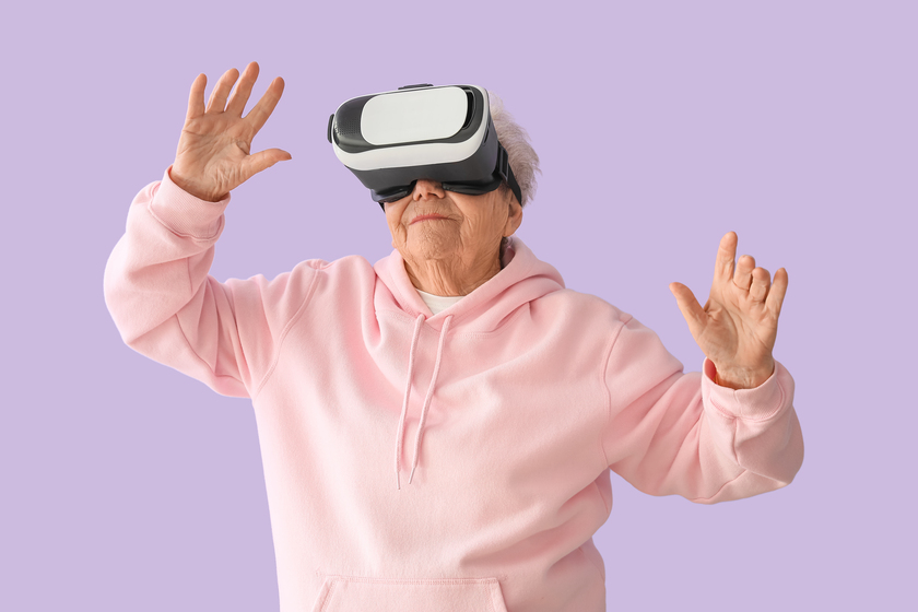 Senior woman in VR glasses on lilac background